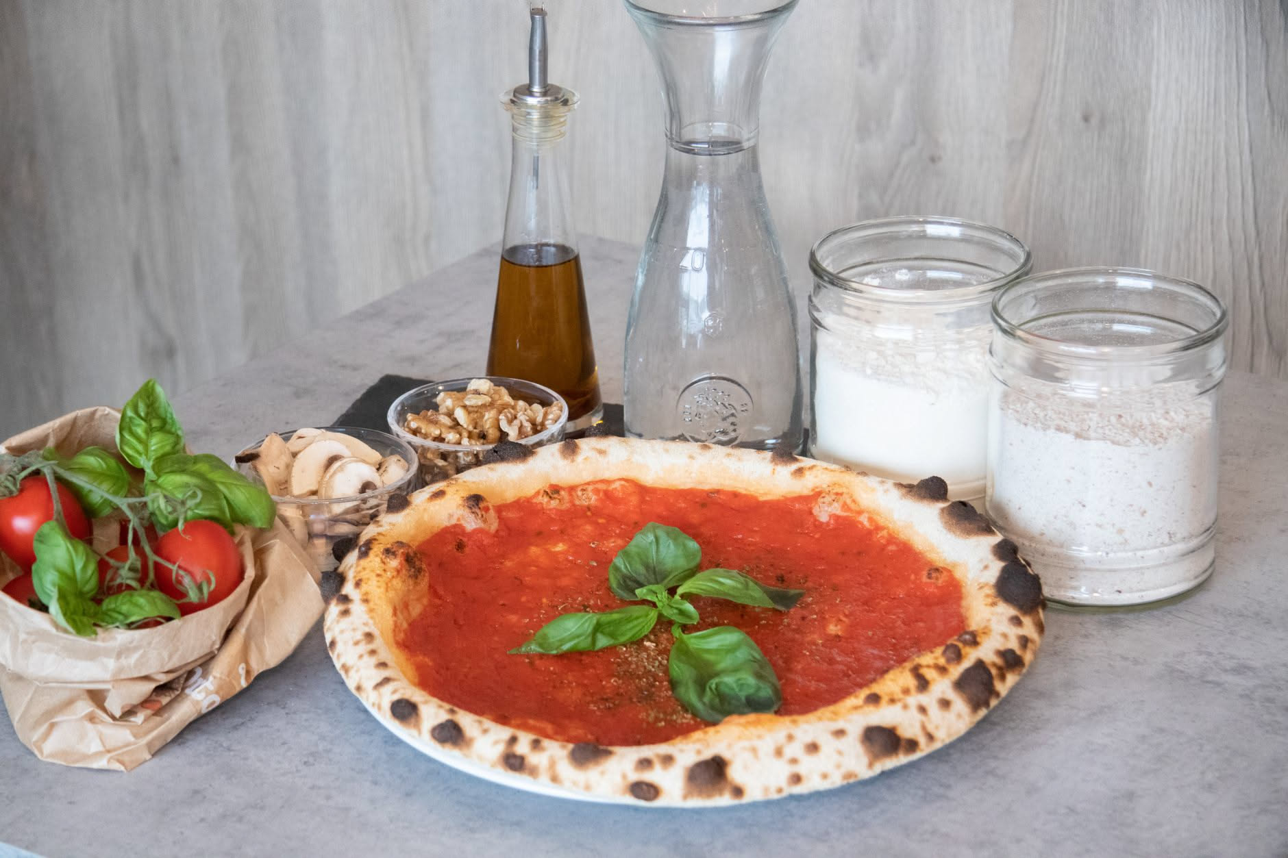 Pizza napoletana con pomodoro rosso vivo, mozzarella bianca, basilico fresco e gocce di olio d'oliva in primo piano su tavolo di legno