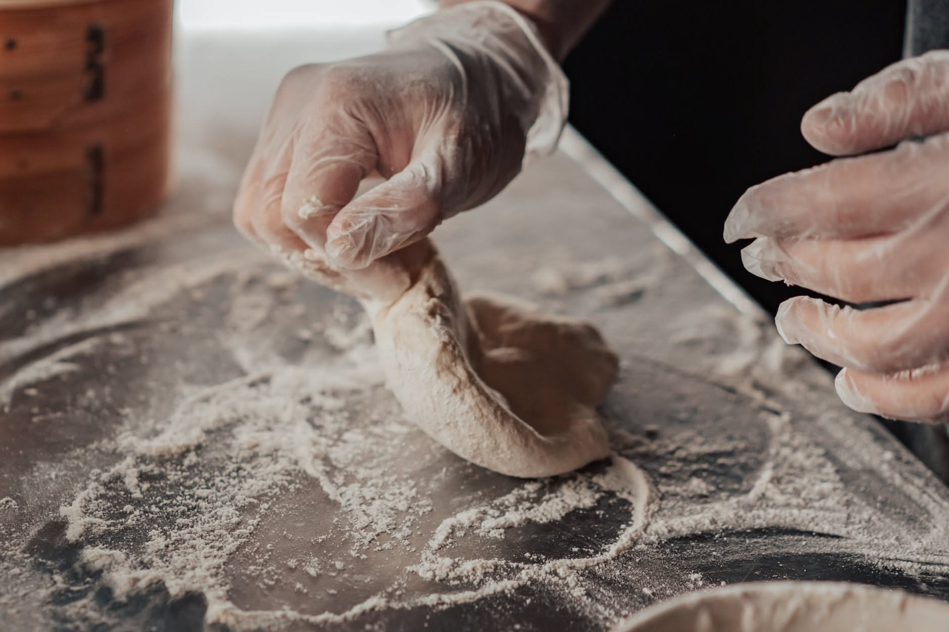 Impasto di pizza in fase di lievitazione dentro un contenitore trasparente, con bolle visibili sulla superficie, accanto a un termometro che segna la temperatura ambiente