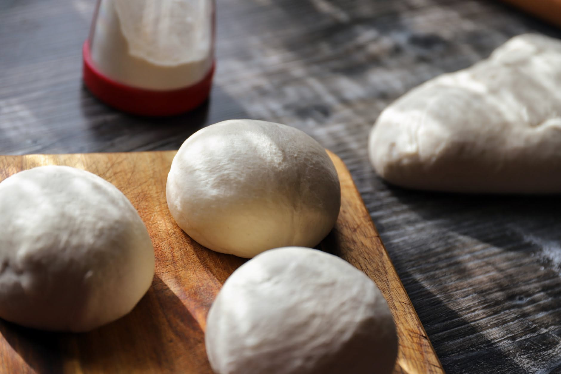 Impasto di pizza gonfiato eccessivamente in una ciotola di acciaio, con bolle visibili sulla superficie e segni di deflazione parziale