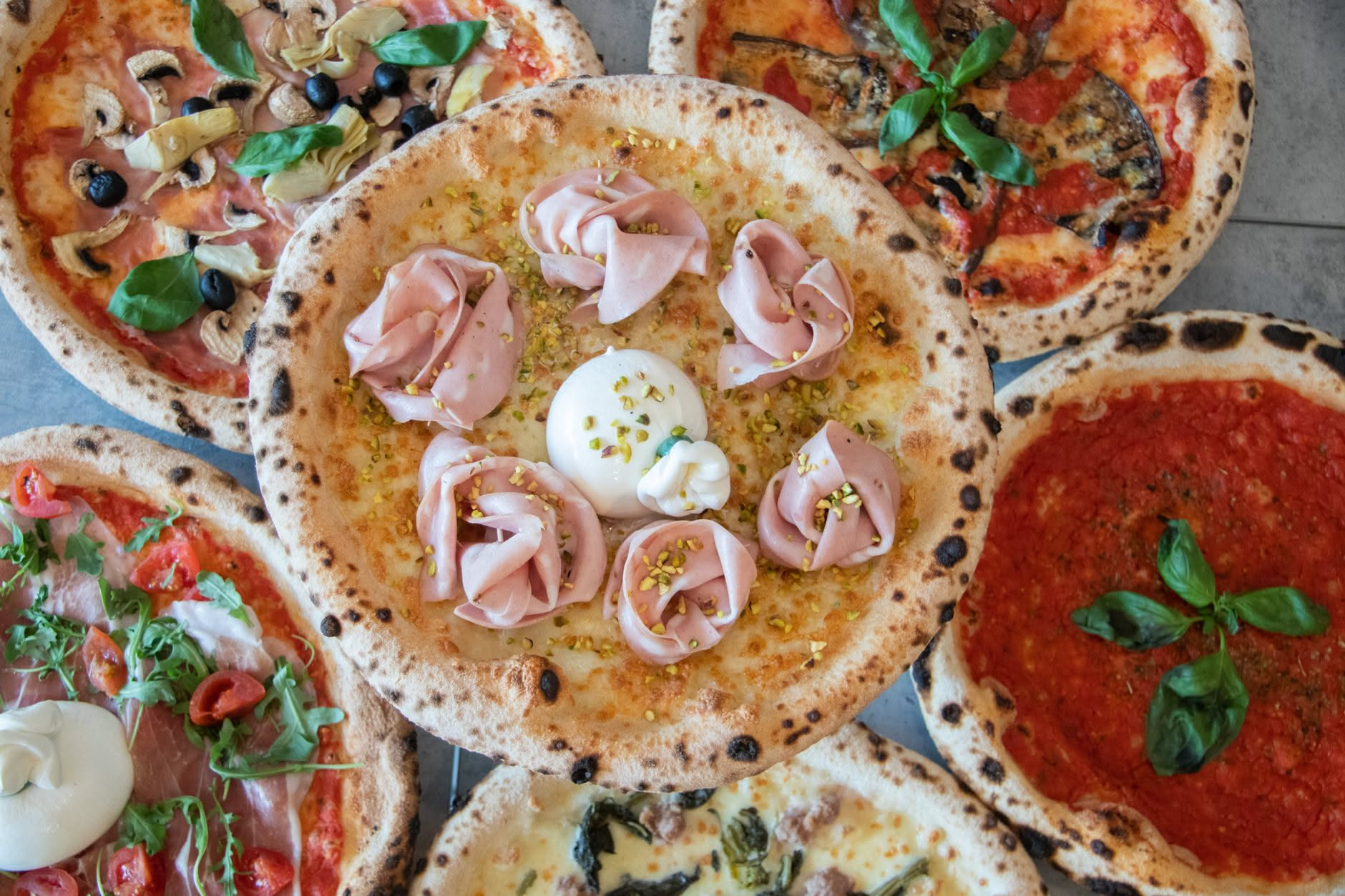 Una pizza contemporanea con cornicione alto e soffiato, farina di tipo integrale e toppings minimalisti, appena sfornata con colore dorato uniforme