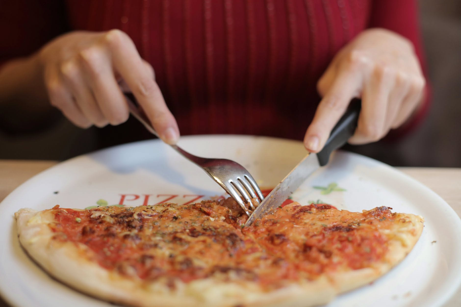 Sezione di pizza con cornicione dorato e croccante, ma impasto crudo e bianco al centro, su piatto di terracotta