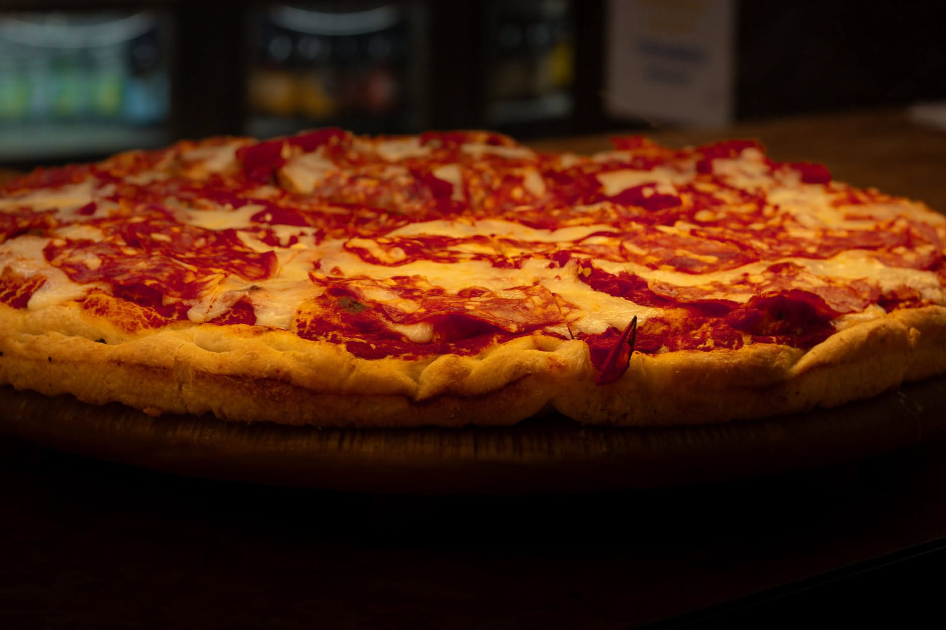 Pizza in teglia appena sfornata, dorata e croccante, con mozzarella fusa, pomodoro rosso brillante e basilico fresco su teglia rettangolare di acciaio