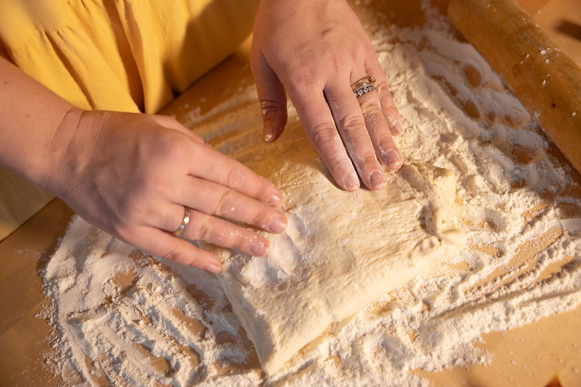 Impasto di pizza in teglia bionda e gonfia che riempie una teglia rettangolare, presa da vicino con dettagli di bolle in superficie e texture alveolata visibile