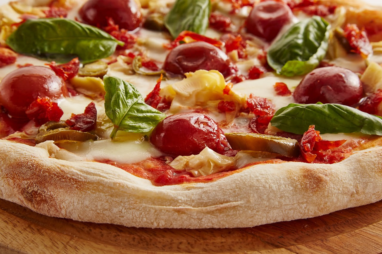 Antica pizzeria napoletana del Settecento con forno a legna, donne che preparano pizza al pomodoro su un banco di legno, muri bianchi e intonaco scrostato