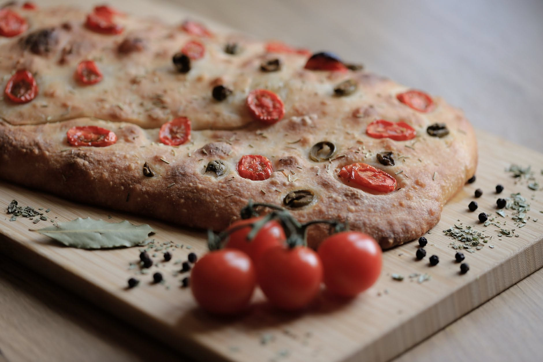 Pomodori, spicchi d'aglio e origano secco disposti su un tagliere di legno consumato, luce naturale calda