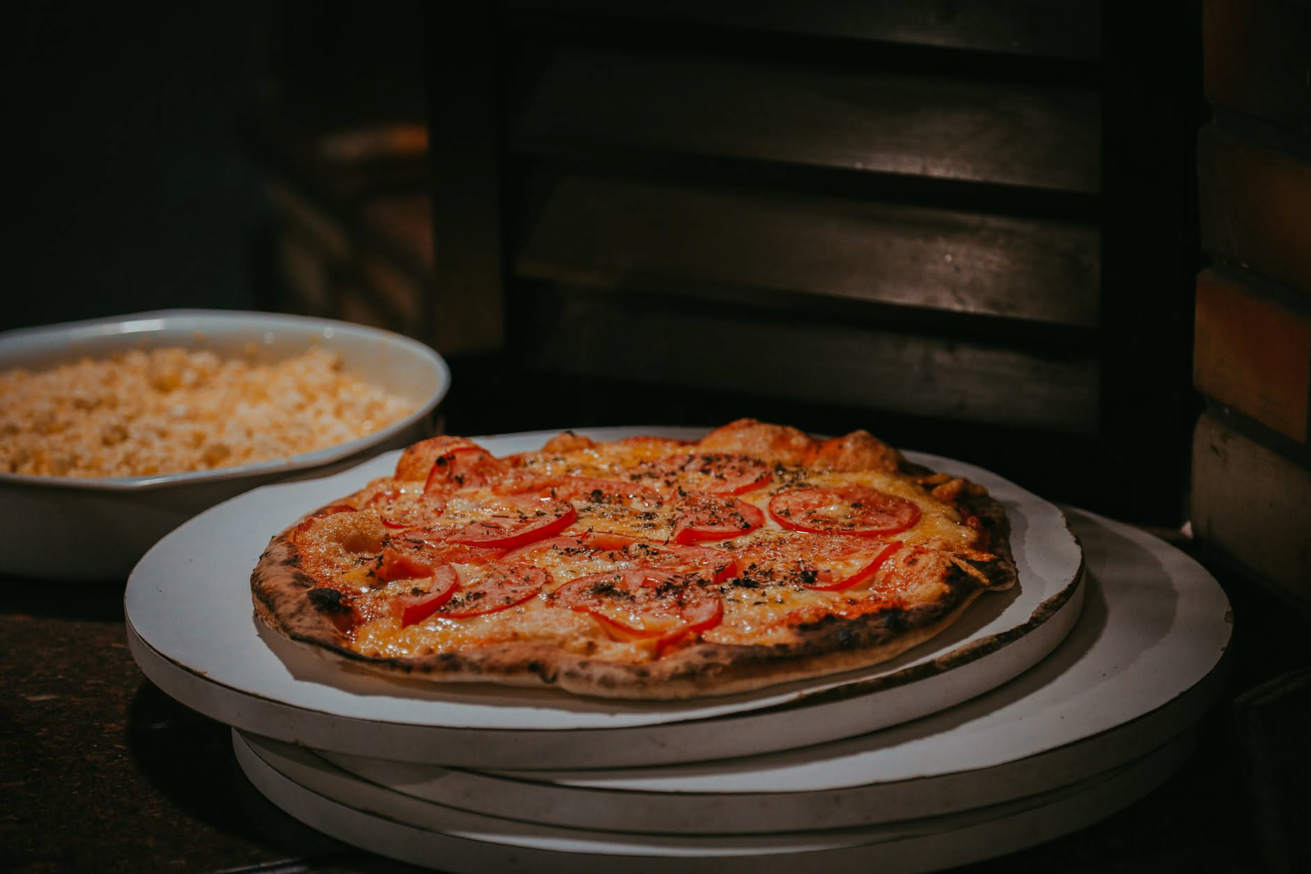 Pizza sollevata con una pala da una pietra refrattaria nel forno di casa, fondo con macchie brune