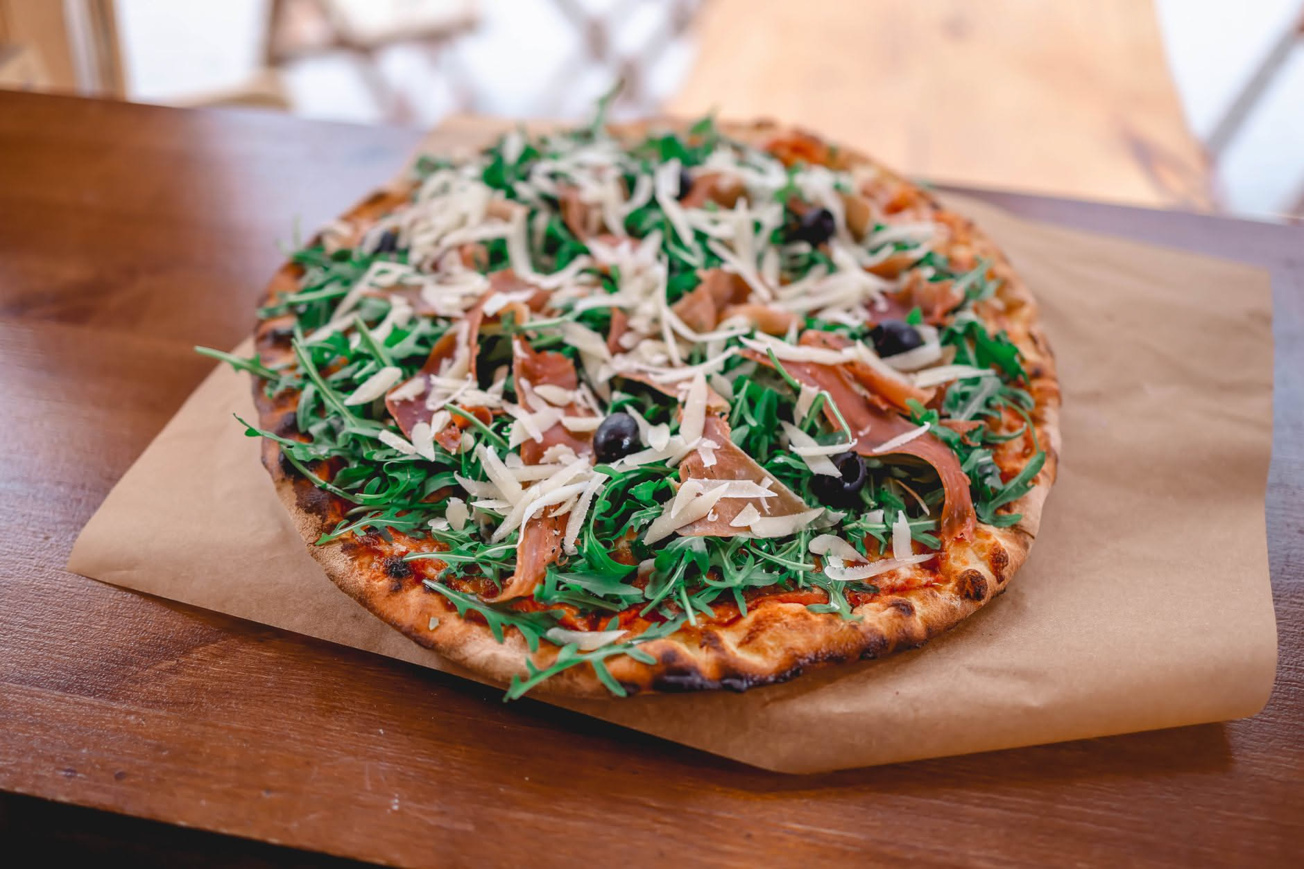 Pizza con fette di prosciutto crudo e rucola fresca aggiunte dopo la cottura