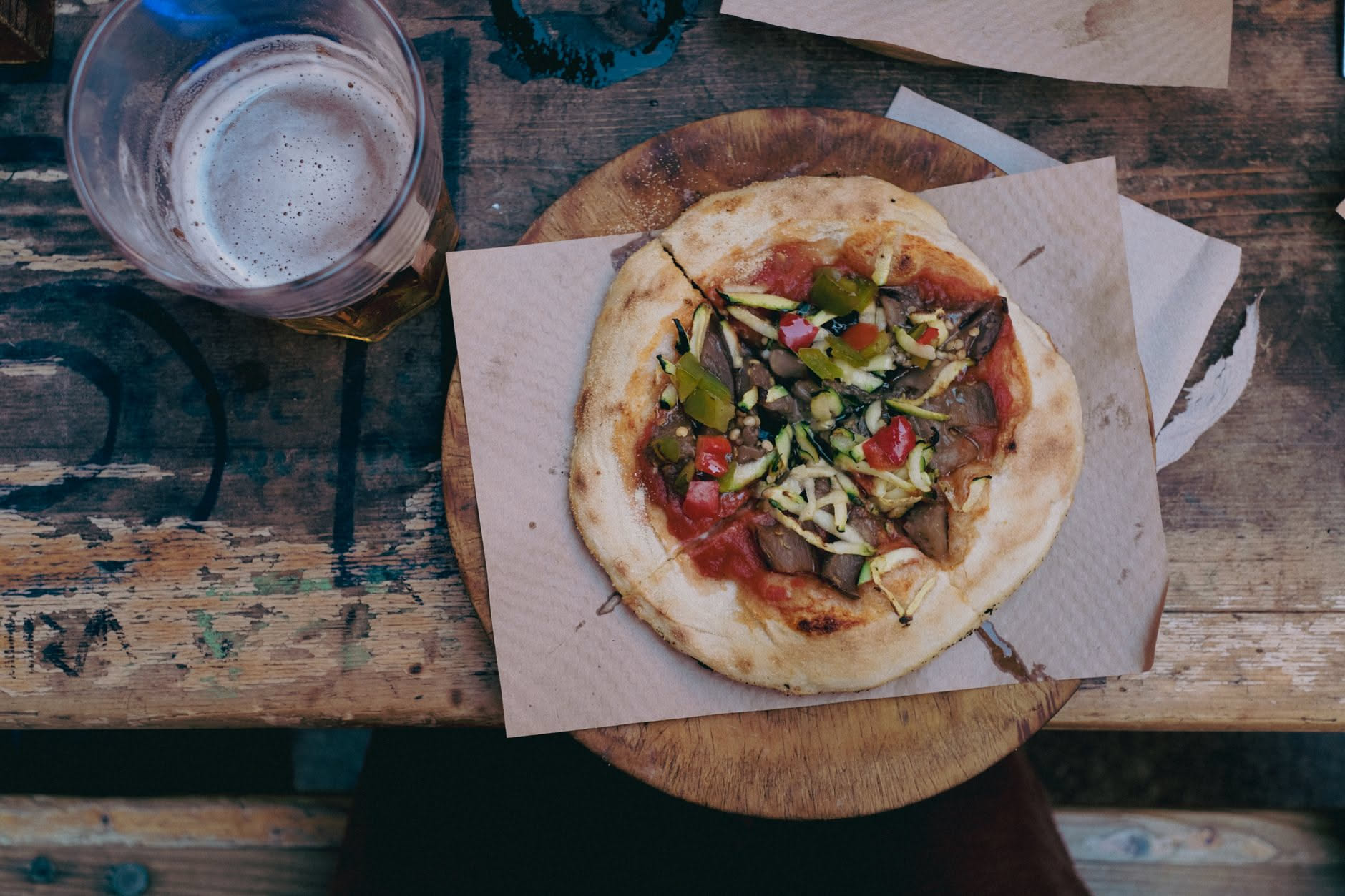Pizza tonda che cuoce su una pietra refrattaria dentro un barbecue a carbone con il coperchio aperto