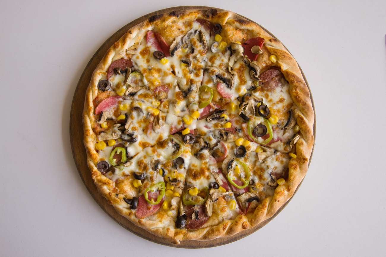 Pizza con salame, funghi, mais e olive